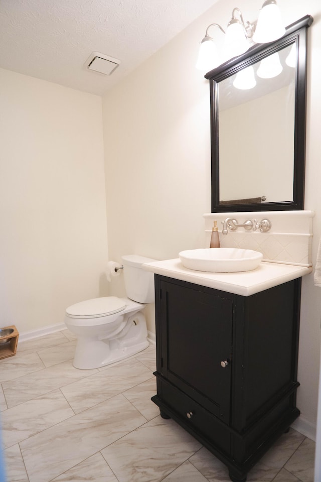 bathroom featuring a textured ceiling, vanity, and toilet