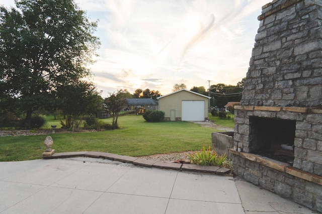 patio terrace at dusk with an outdoor structure, a garage, and a yard