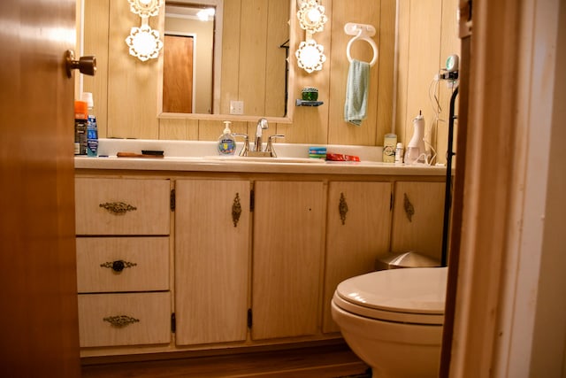 bathroom featuring vanity, toilet, hardwood / wood-style flooring, and wood walls