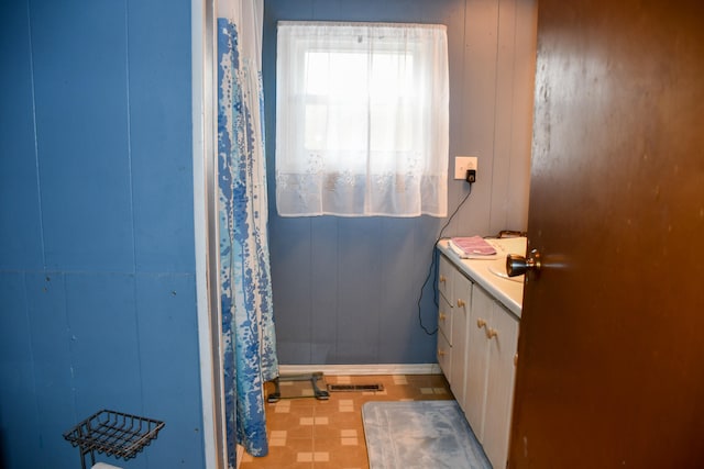 bathroom featuring a shower with shower curtain, wooden walls, and vanity