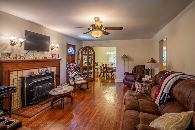 living room featuring ceiling fan with notable chandelier, wood-type flooring, and a fireplace