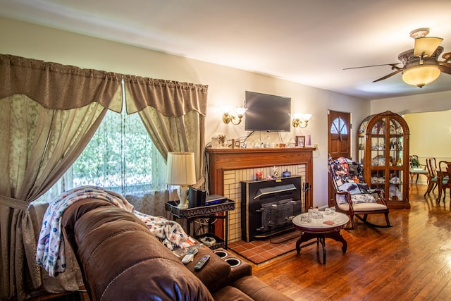 living room with a wood stove, wood-type flooring, a fireplace, and ceiling fan