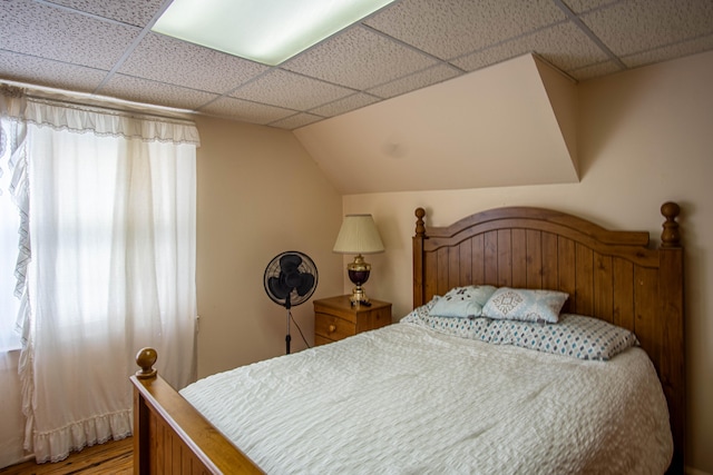 bedroom with multiple windows, wood-type flooring, and a drop ceiling