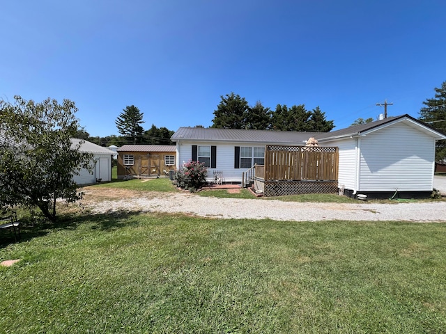 back of house featuring an outbuilding, a yard, and a wooden deck