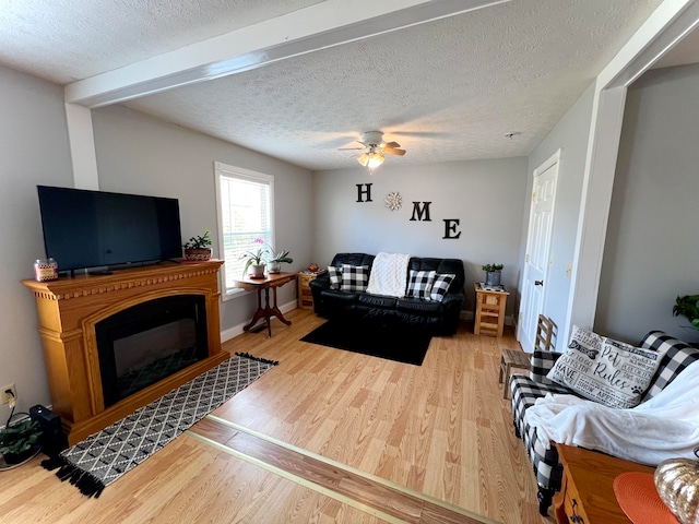 living room featuring ceiling fan, a textured ceiling, and light hardwood / wood-style flooring