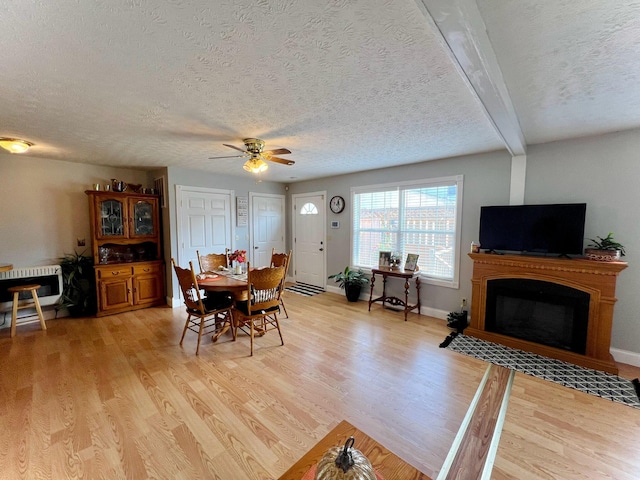 dining area featuring beamed ceiling, a textured ceiling, heating unit, ceiling fan, and light hardwood / wood-style floors