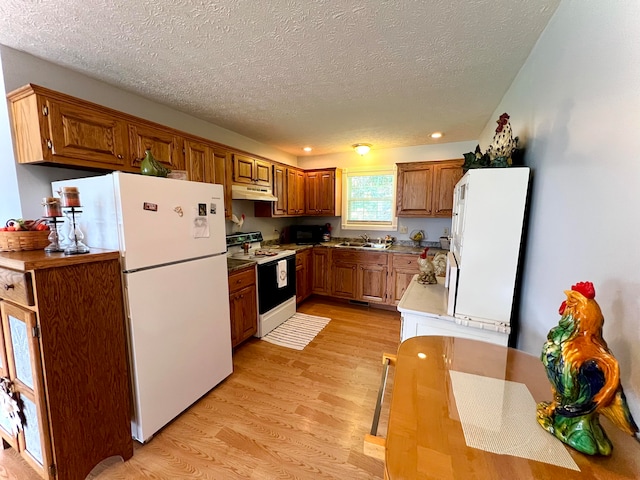 kitchen with white appliances, light hardwood / wood-style flooring, sink, and a textured ceiling