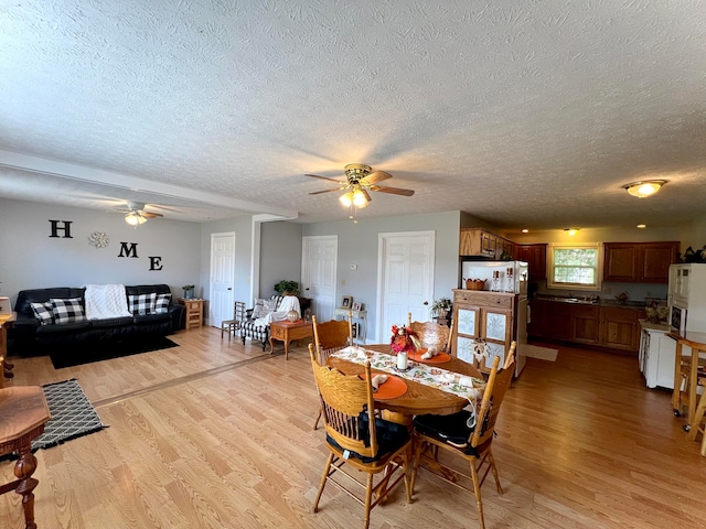 dining area with a textured ceiling, ceiling fan, and light hardwood / wood-style floors