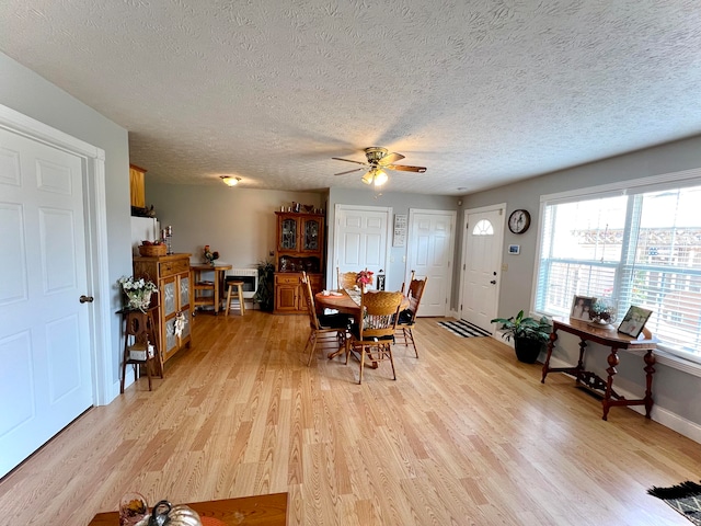 dining room with light wood-type flooring, a textured ceiling, and ceiling fan