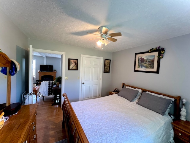 bedroom with ceiling fan, dark hardwood / wood-style floors, and a textured ceiling