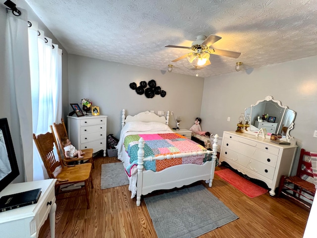 bedroom with hardwood / wood-style floors, ceiling fan, and a textured ceiling