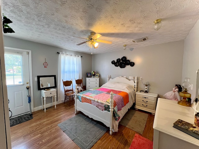 bedroom with ceiling fan, dark hardwood / wood-style flooring, and a textured ceiling