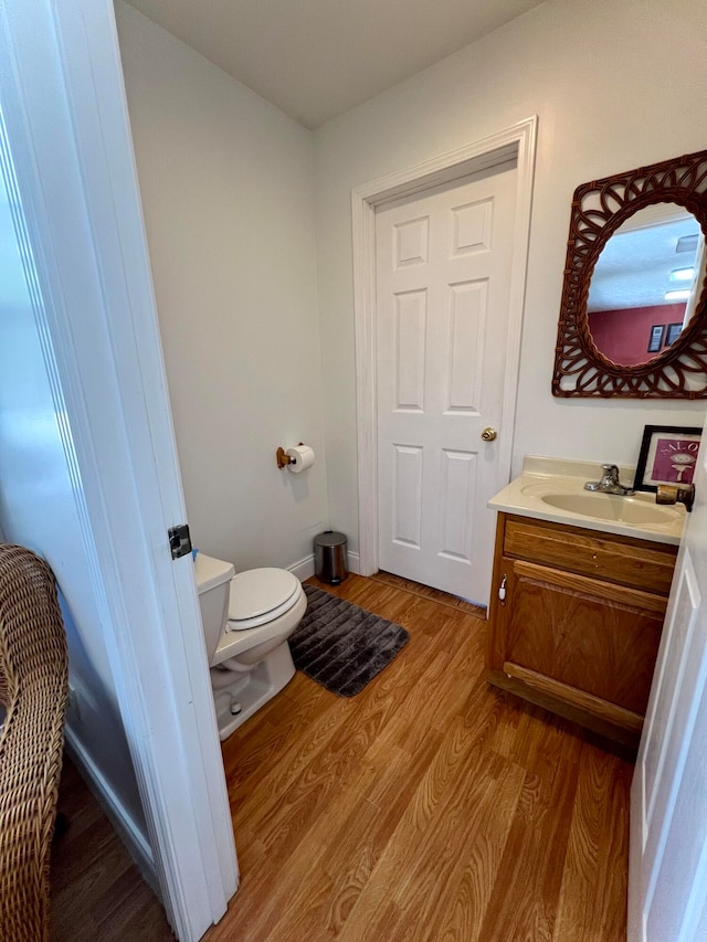 bathroom with toilet, hardwood / wood-style flooring, and vanity