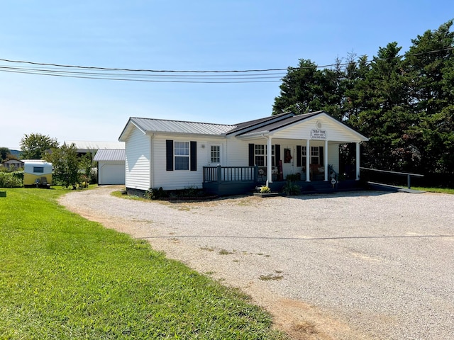 ranch-style home with a porch, a garage, an outbuilding, and a front yard