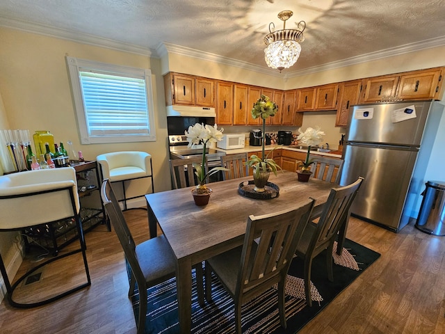 dining area with ornamental molding, dark hardwood / wood-style flooring, a notable chandelier, and a textured ceiling