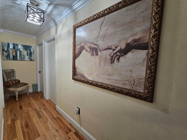 corridor featuring wood-type flooring, a textured ceiling, and ornamental molding