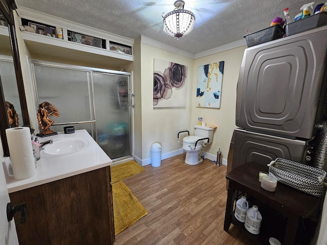 bathroom with toilet, a shower with door, vanity, a textured ceiling, and wood-type flooring