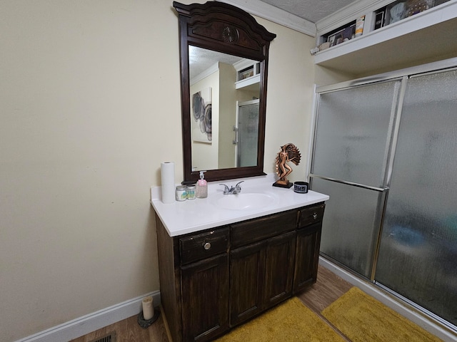 bathroom featuring a shower with door, vanity, a textured ceiling, ornamental molding, and hardwood / wood-style flooring