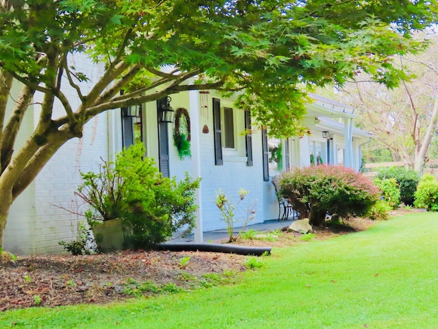 view of side of property with brick siding and a lawn