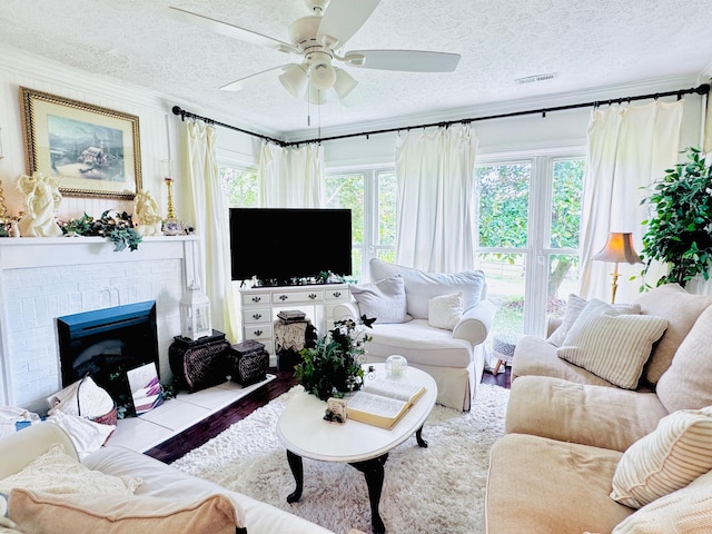 living room with a textured ceiling, a brick fireplace, and ceiling fan