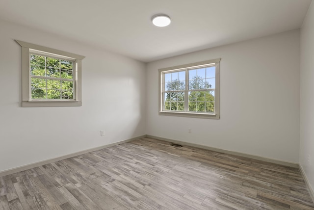 unfurnished room featuring a wealth of natural light and hardwood / wood-style floors