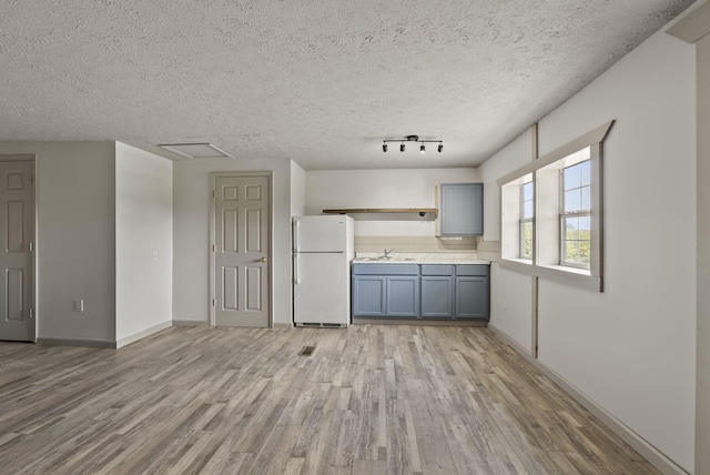 kitchen featuring a textured ceiling, light hardwood / wood-style flooring, sink, and white refrigerator