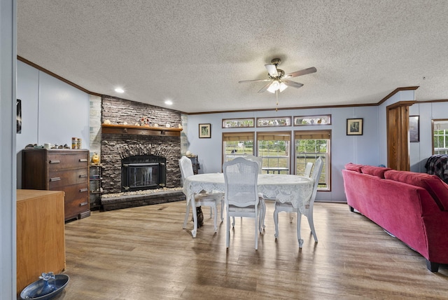 dining room with a fireplace, ornamental molding, ceiling fan, and a textured ceiling