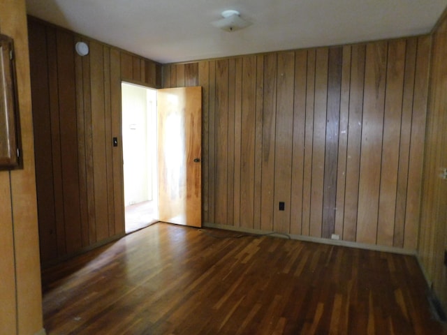 spare room with dark wood-type flooring and wooden walls