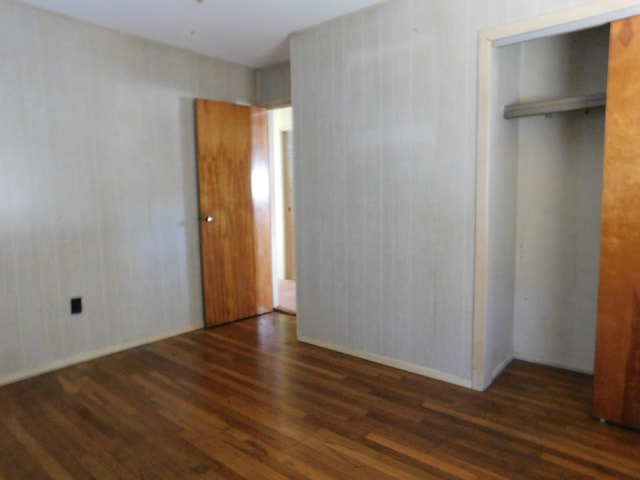 unfurnished bedroom with dark wood-type flooring and a closet