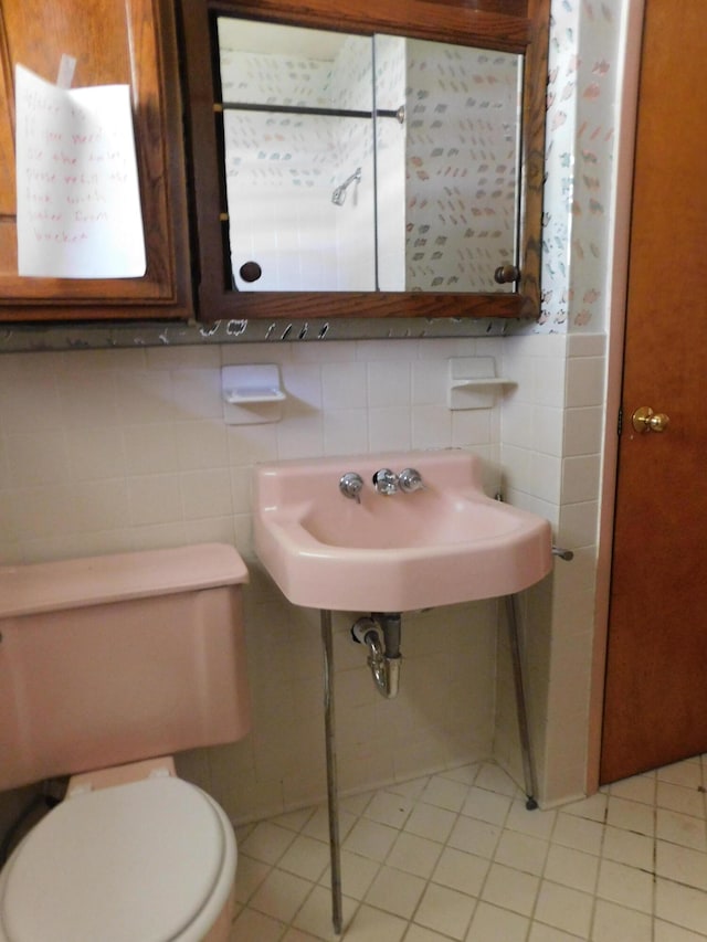 bathroom featuring tasteful backsplash, tile patterned flooring, tile walls, toilet, and sink