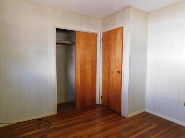 unfurnished bedroom with a closet and dark hardwood / wood-style flooring