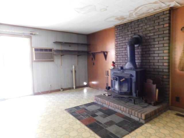 unfurnished living room with an AC wall unit, a wood stove, and wooden walls