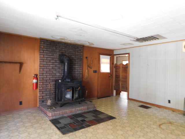 living room with a wood stove and wooden walls