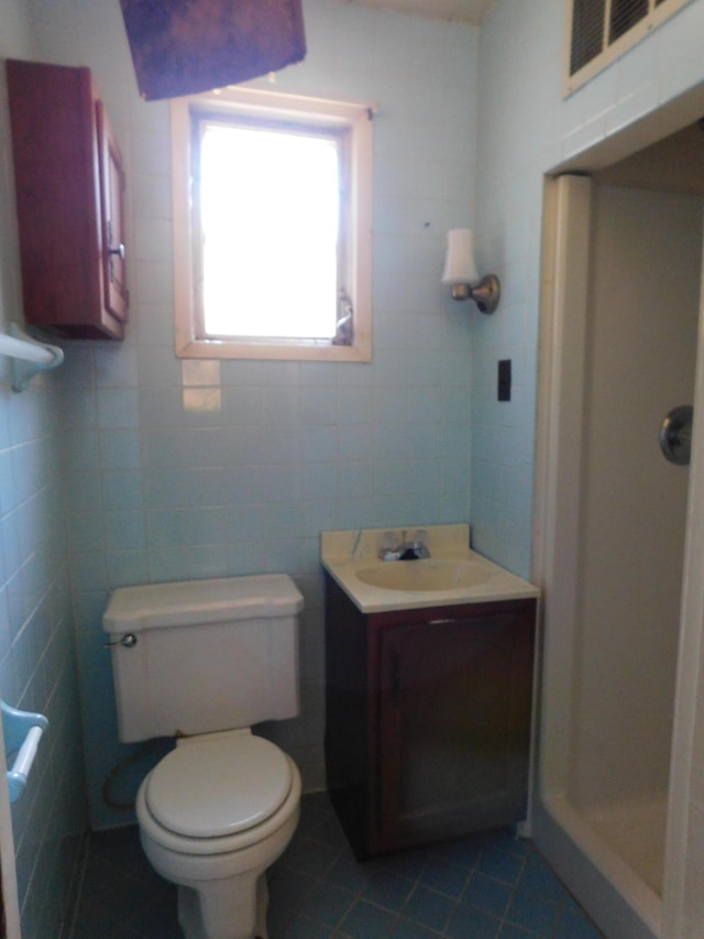 bathroom with a shower, tile walls, toilet, and vanity