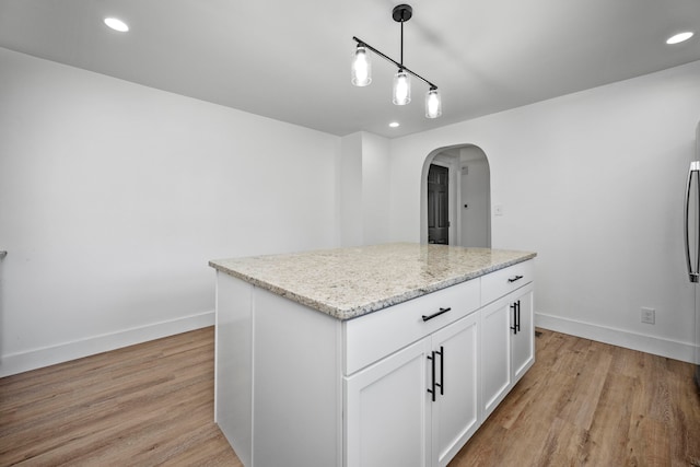 kitchen featuring white cabinetry, a kitchen island, decorative light fixtures, and light hardwood / wood-style floors