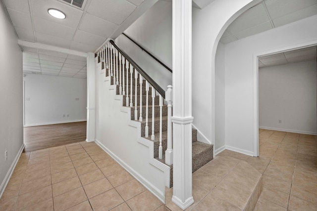 staircase featuring tile patterned flooring and a paneled ceiling