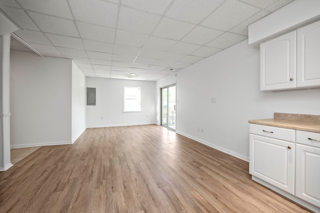 interior space featuring light hardwood / wood-style flooring, a paneled ceiling, and electric panel