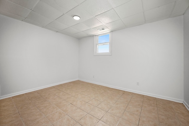 empty room featuring a paneled ceiling and light tile patterned flooring