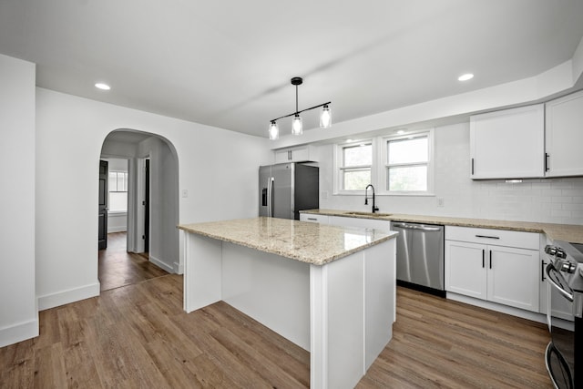 kitchen featuring white cabinetry, a center island, hanging light fixtures, appliances with stainless steel finishes, and light hardwood / wood-style floors