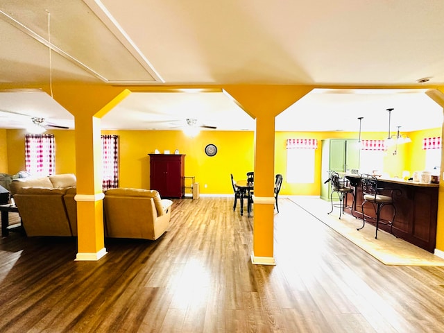 interior space with hardwood / wood-style flooring, ceiling fan, and bar area