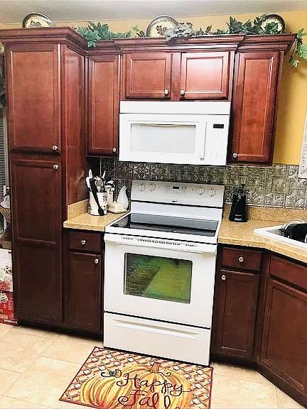 kitchen featuring tasteful backsplash, sink, white appliances, and light tile patterned flooring