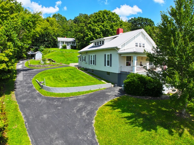 exterior space featuring a lawn, a chimney, and curved driveway
