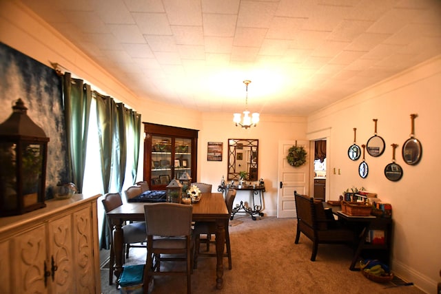 dining area with carpet flooring, crown molding, baseboards, and a chandelier