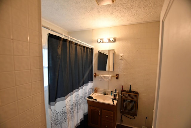 full bathroom with heating unit, vanity, tile walls, and a textured ceiling