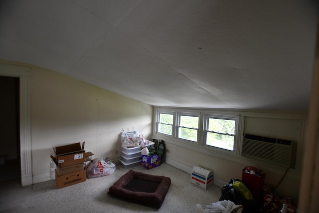 additional living space with an AC wall unit, carpet, and vaulted ceiling