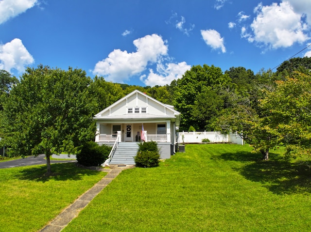 bungalow-style house with covered porch, fence, and a front yard