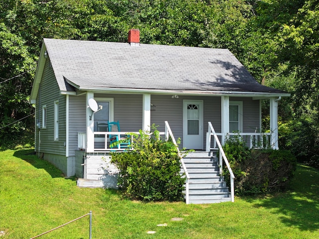 view of front of home with stairs, a front yard, covered porch, a shingled roof, and a chimney