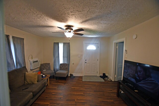 living area featuring a textured ceiling, baseboards, an AC wall unit, ceiling fan, and dark wood-type flooring