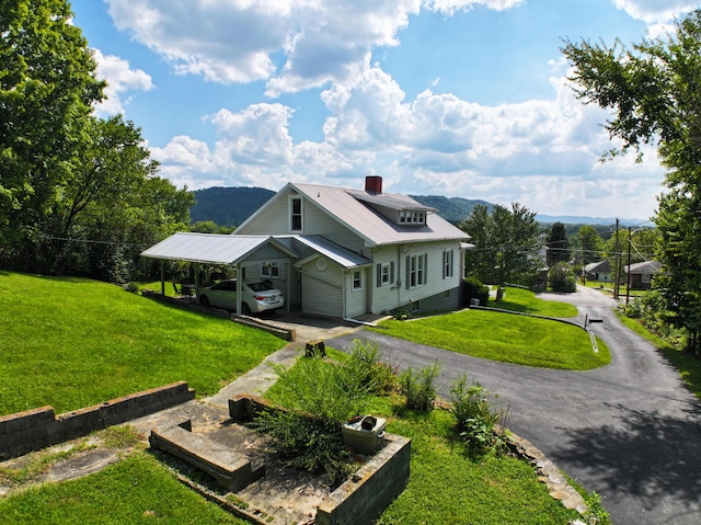 view of front of property featuring driveway, a chimney, a mountain view, and a front yard