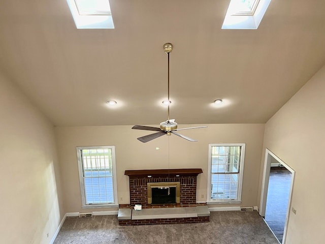 unfurnished living room with carpet, ceiling fan, lofted ceiling with skylight, and a fireplace